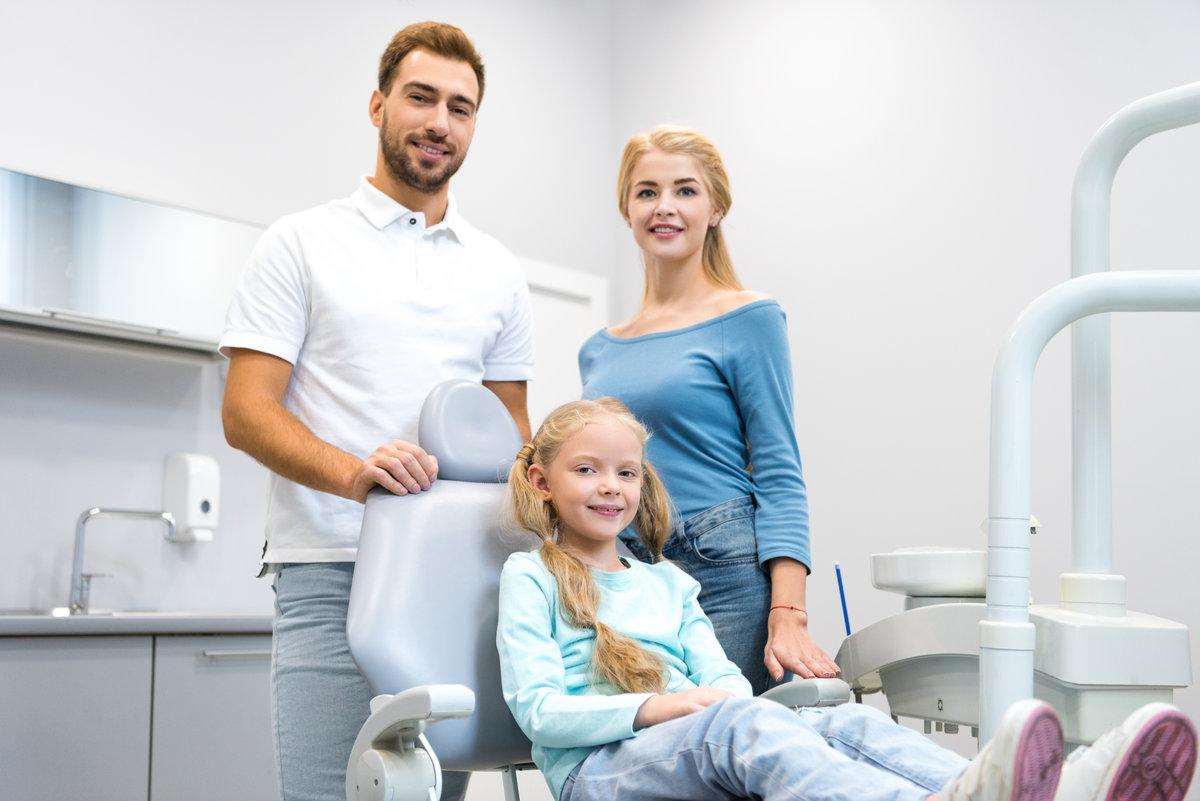happy young family looking at camera at dentist office happy young family looking at camera at dentist office