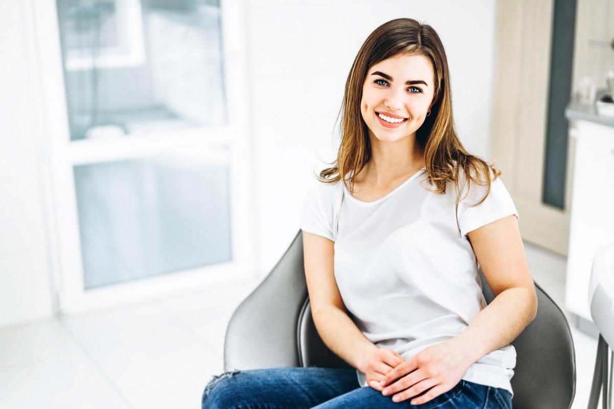 Pretty happy and smiling dental patient sitting in the dental chair at the dental office. Pretty happy and smiling dental patient sitting in the dental chair at the dental office