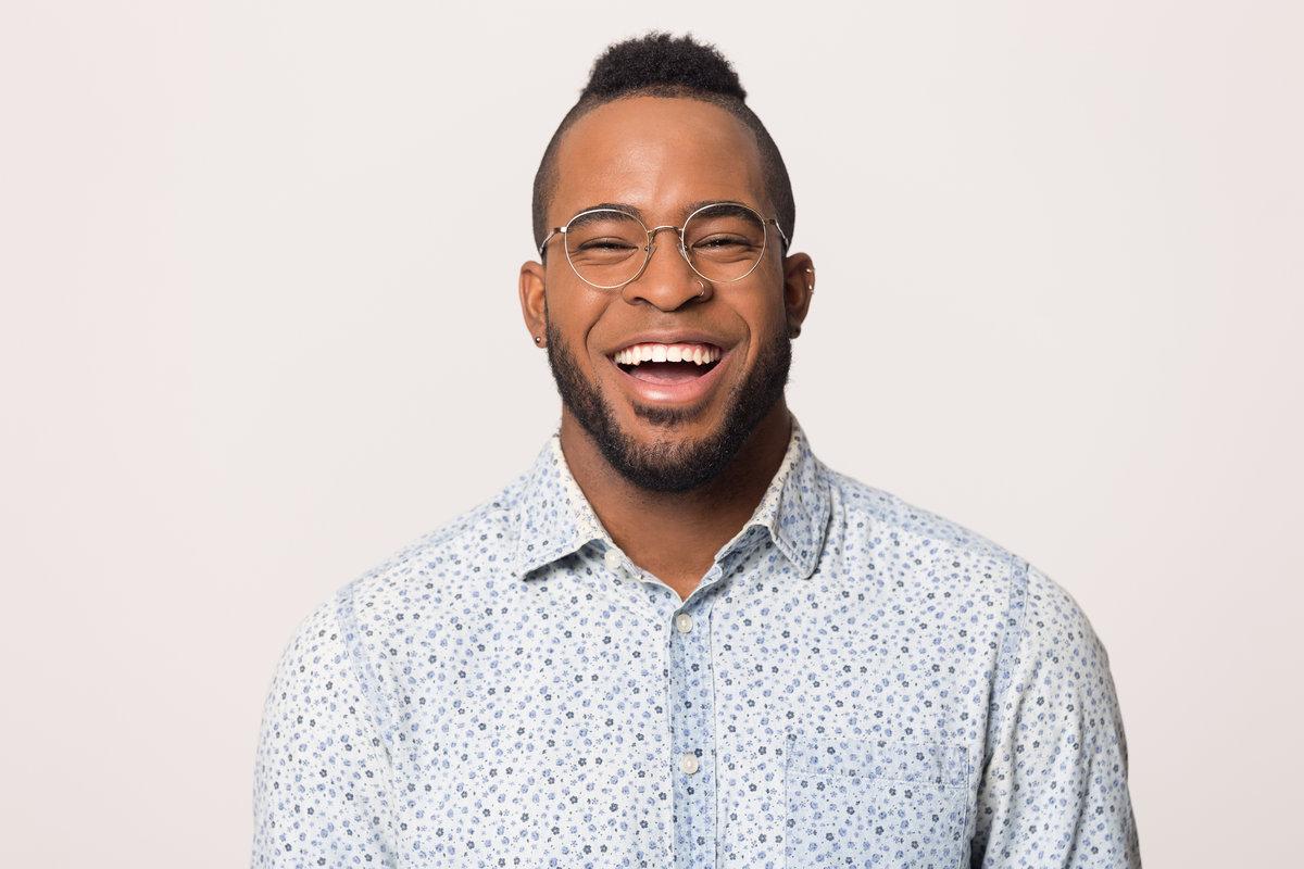 Head shot portrait laughing African American man in glasses isolated Head shot portrait of cheerful laughing young African American man in glasses isolated on studio background copy space, funny guy with wide beaming healthy smile looking at camera, feeling happy