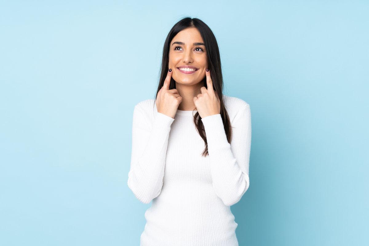 Young caucasian woman isolated on blue background smiling with a happy and pleasant expression Young caucasian woman isolated on blue background smiling with a happy and pleasant expression