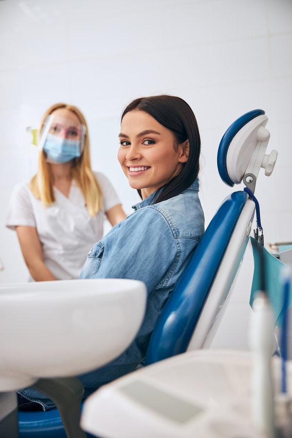 Positive delighted patient looking straight at camera Charming young female person demonstrating her smile while being at dental examination